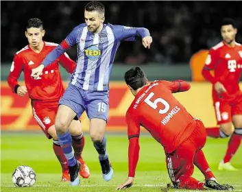  ?? DPA-BILD: GORA ?? Stabil ist anders: Berlins Vedad Ibisevic (Mitte) spielt den Ball, Münchens Mats Hummels (rechts) und James Rodriguez (links) versuchen, an ihn heranzukom­men.