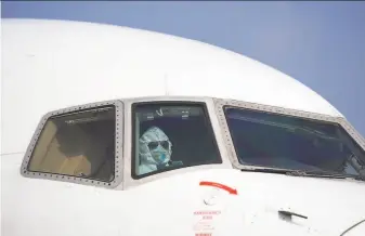  ?? Xinhua News Agency ?? A pilot wearing a protective suit parks a cargo plane at Wuhan’s airport in Hubei province. Wuhan is the epicenter of a new virus that has killed more than 130 and sickened thousands.