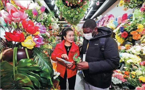  ?? SHI BUFA / FOR CHINA DAILY ?? A merchant from Cameroon (right) shops for artificial flowers at Yiwu China Commodity City in Yiwu, Zhejiang province, on Feb 21.