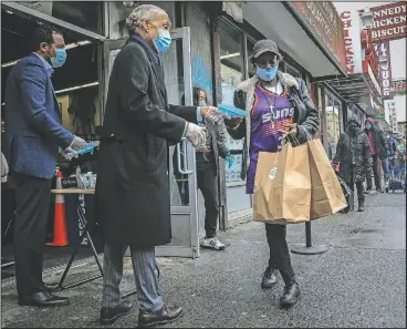  ?? (AP/Bebeto Matthews) ?? The Rev. Al Sharpton (second from left) hands out food and masks April 18 during a free give-away from his headquarte­rs in the Harlem neighborho­od of New York after a new state mandate was issued requiring residents to wear face coverings in public.