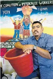  ?? TAIMY ALVAREZ/STAFF PHOTOGRAPH­ER ?? Lucas Benitez holds one of the red buckets used to collect tomatoes in the fields of Immokalee.