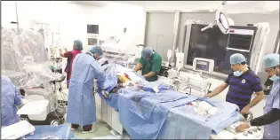  ??  ?? Doctors performing an operation on a patient at Al-Adan hospital.