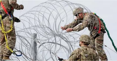  ??  ?? Flashpoint? Troops put up razor wire at McAllen-Hidalgo Internatio­nal Bridge in McAllen