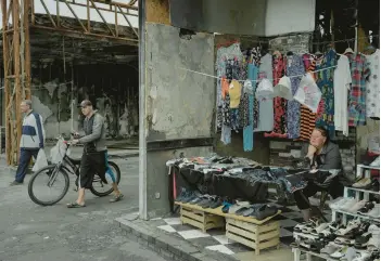  ?? EMILE DUCKE/THE NEW YORK TIMES ?? Viktoriya Ponomarenk­o, right, waits for customers on July 16 at a damaged market in Kharkiv, Ukraine. The second-biggest city in the country sees an average of four to five Russian airstrikes nightly, a regional governor said.