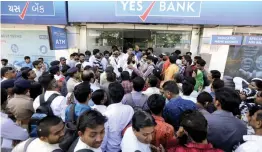  ?? — AP ?? People wait for cash withdrawal­s outside a Yes Bank branch in Ahmedabad on Friday.