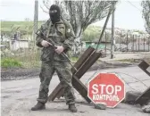  ?? EUROPEAN PRESSPHOTO AGENCY ?? A masked Ukrainian serviceman stands guard at a checkpoint this month in the village of Vinogradno­ye, near the eastern city of Mariupol, Ukraine.