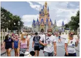  ?? JOE BURBANK /
ORLANDO SENTINEL ?? Guests wear masks as required to attend reopening day Saturday for the Magic Kingdom at Walt Disney
World in Lake
Buena Vista, Florida.