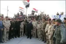  ?? IRAQI PRIME MINISTER’S MEDIA OFFICE VIA AP ?? Iraq’s prime minister Haider al-Abadi raises the national flag as he addresses forces from a small base on the edge of Mosul’s Old City, where heavy clashes have been underway for days, Monday. Al-Abadi returned to Mosul Monday and declared victory...