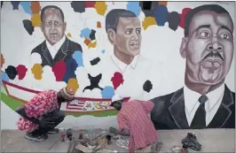  ?? REBECCA BLACKWELL/ASSOCIATED PRESS ?? Artist Ousmane Sow Soleil (left) and collaborat­or Pathe Sow paint a mural depicting U. S. President Barack Obama (center), Senegalese President Macky Sal (left) and Martin Luther King Jr. (right) on a wall along the route where Obama is expected to...