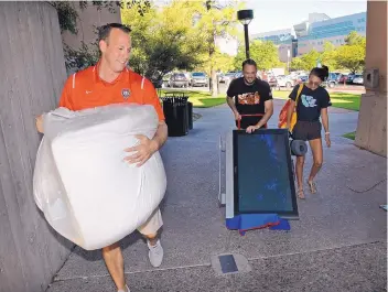  ?? JIM THOMPSON/JOURNAL ?? UNM Director of Athletics Eddie Nuñez carries a bag of stuff into DeVargas Hall for Samantha Lambrecht as she moved in on Friday. Also helping move a TV is her father, Michael Lambrecht.