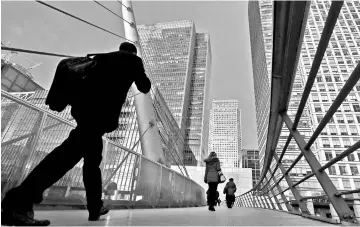  ?? — Reuters photo ?? People walk through the Canary Wharf financial district of London.