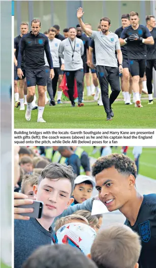  ??  ?? Building bridges with the locals: Gareth Southgate and Harry Kane are presented with gifts (left); the coach waves (above) as he and his captain lead the England squad onto the pitch, while Dele Alli (below) poses for a fan