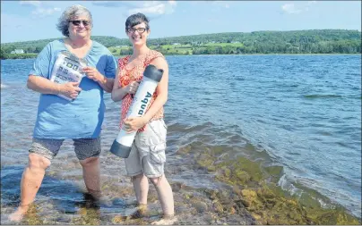  ?? CAPE BRETON POST PHOTO ?? Annamarie Hatcher, left, and Sarah Penney use an underwater viewer to scan the bottom of the Bras d’Or Lake for plants and animals at the East Bay sandbar. The public is encouraged to help collect data on the Bras d’Or ecosystem during the third annual...