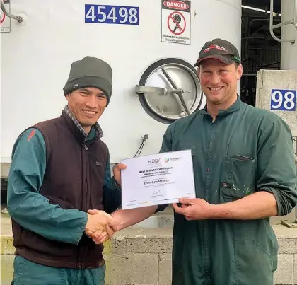  ??  ?? Waitarere Beach dairy farmer Simon Easton presenting Erwin Manego with the primary ITO certificat­e in level 3 dairy livestock husbandry.