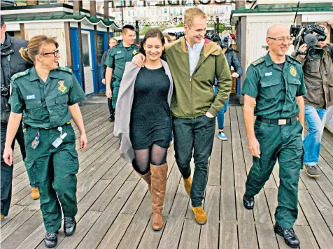  ??  ?? Fisherman Sam Quilliam with his girlfriend Sandra Souto on Boscombe Pier in Bournemout­h, flanked by the paramedic team which saved him, including Matt Harrison, far right