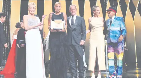  ?? — AFP photo ?? Julia Ducournau (second left) poses on stage with US actress Sharon Stone (left), French actor Vincent Lindon (centre), French actress Agathe Rousselle (second right) and Lee after she won the Palme d’Or for her film ‘Titane’ during the closing ceremony of the 74th edition of the Cannes Film Festival in Cannes, southern France.