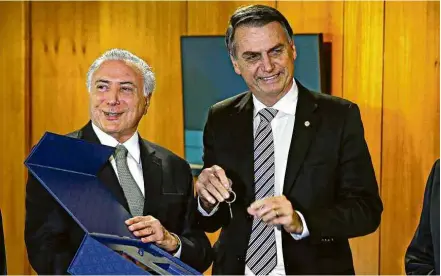  ?? Pedro Ladeira/Folhapress ?? Michel Temer entrega a Jair Bolsonaro a chave do CCBB, onde ficará o gabinete de transição