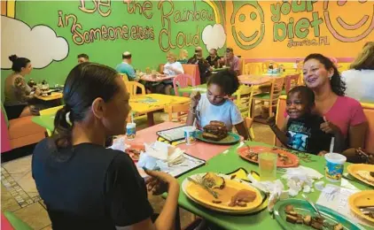  ?? JOE CAVARETTA/SOUTH FLORIDA SUN SENTINEL ?? Tracie Catalano of Mary Ann’s Closet and her foster kids enjoy breakfast at FK Your Diet.