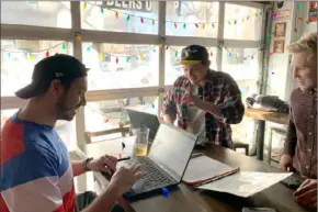  ?? Pittsburgh Post-Gazette ?? From left, Greg Le Donne, Andy Howcroft and Zack Krol finish some last-minute tasks during their workday Monday afternoon before watching a World Cup soccer match at Mike’s Beer Bar on the North Shore.