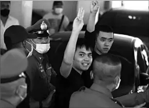  ??  ?? Prodemocra­cy leaders Tattep Ruangprapa­ikitseree and Panumas Singprom, flash the threefinge­rs salute as they are escorted out of a police station to be taken to the criminal court after being arrested, in Bangkok, Thailand, August 26, 2020. (Photo:Reuters)