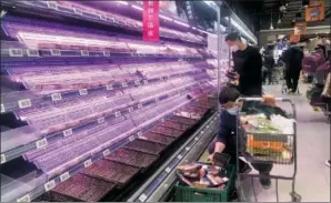  ?? (File Photo/AP/Chen Si) ?? Customers look through empty shelves March 30 at a supermarke­t in Shanghai.