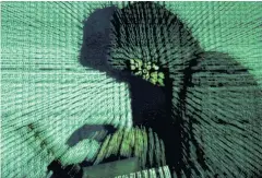  ?? REUTERS ?? A man holds a laptop computer as cyber code is projected on him in this illustrati­on picture taken in 2017.