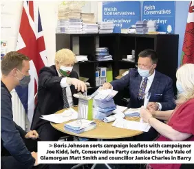  ??  ?? > Boris Johnson sorts campaign leaflets with campaigner Joe Kidd, left, Conservati­ve Party candidate for the Vale of Glamorgan Matt Smith and councillor Janice Charles in Barry