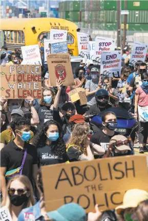  ?? Sarahbeth Maney / The Chronicle ?? Marchers call for defunding police at a Juneteenth protest in Oakland on June 19. Oakland police have announced a sudden surge in homicides in late June and July.