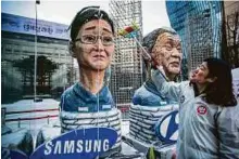  ?? Bloomberg ?? A protester sweeps effigies of Samsung’s Jay Y. Lee (left) and Hyundai Motor Co.’s Chung Mong-koo outside Samsung’s Seocho office building in Seoul on Friday.