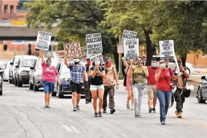  ?? Photos by Robin Jerstad / Contributo­r ?? Marchers lead a caravan of vehicles through downtown during the National Day of Protest. The event was sponsored by the San Antonio chapter of the Party for Socialism & Liberation.