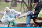  ??  ?? MINSK: A volunteer of the Street Medicine movement, wearing protective equipment, tends to the foot wound of a man as they provide medical care to homeless people in Minsk. — AFP