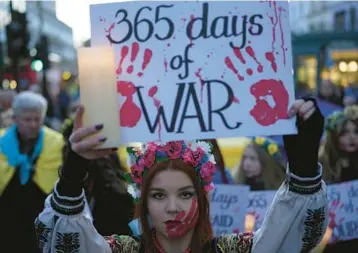  ?? KIN CHEUNG/AP ?? A Ukraine supporter holds a placard marking the first anniversar­y of the war during a protest Friday in London.