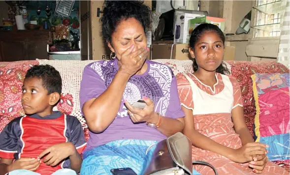  ?? Photo: Vilimoni Vaganalau ?? Salome Daucakacak­a holds on to an ID card of her late husband with her children, Lavenia Nodrakoro (right), and Sekove Raibono at their home in Sawani on July 29, 2017.