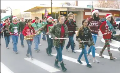  ?? Westside Eagle Observer/SUSAN HOLLAND ?? Members of the Gravette High School marching band, dressed in colorful holiday attire, step lively down Main Street during the Gravette Christmas parade. The band entertaine­d the crowd with holiday carols and received the trophy for best use of the parade theme, “Sounds of the Season.”