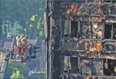  ?? RICK FINDLER / PA VIA ASSOCIATED PRESS ?? Firefighte­rs survey the damage to the fire-gutted Grenfell Tower in the borough of Kensington and Chelsea, west London, on Friday. A deadly blaze engulfed the 24-story building on Wednesday, killing at least 17 people.