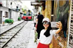  ?? MANAN VATSYAYANA/AFP ?? A woman takes a selfie as a train passes in Hanoi.