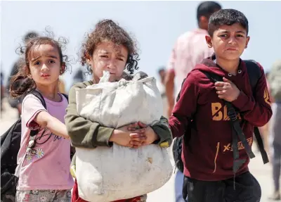  ?? AFP ?? Children walk with other displaced Palestinia­ns taking the coastal Rashid road to return to Gaza City as they pass through Nuseirat in the central Gaza Strip on Friday.