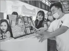  ?? HU YIYI / FOR CHINA DAILY ?? A visitor (right) checks out cosmetic contact lenses at a booth during the China Joy exhibition on July 31, 2020.