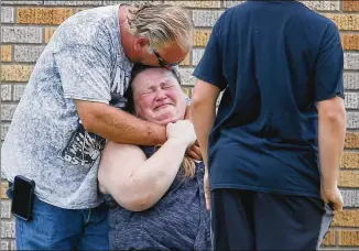  ?? MICHAEL CIAGLO / HOUSTON CHRONICLE ?? A man hugs a woman outside the Alamo Gym where parents wait to reunite with their kids following the shooting at Santa Fe High School on Friday.