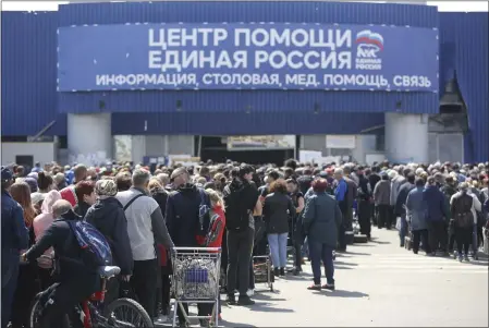  ?? ALEXEI ALEXANDROV — THE ASSOCIATED PRESS ?? Local civilians line up to get humanitari­an aid distribute­d in the United Humanitari­an Center in Mariupol, in territory under the government of the Donetsk People’s Republic, eastern Ukraine, Monday with a poster reading ‘Help center. United Russia’.