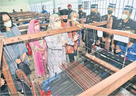  ?? — Informatio­n Department photo ?? Tunku Azizah (third left ), with Juma’ani on her right, observes the songket-weaving process during the visit.