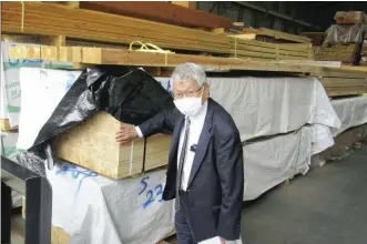  ?? The Yomiuri Shimbun ?? Ichijo-lumber Co. President Tatsuo Ichijo shows timber at a lumber market in Koto Ward, Tokyo.