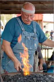  ?? Westside Eagle Observer/RANDY MOLL ?? Lin Rhea, of Prattsvill­e, a member of the American Bladesmith Associatio­n, heats up a piece of iron as he demonstrat­es the art to a crowd of visitors Sept. 11 at the Tired Iron of the Ozarks fall show in Gentry. Members of the American Bladesmith Associatio­n and the Blacksmith Organizati­on of Arkansas were at the annual show and talking with spectators.