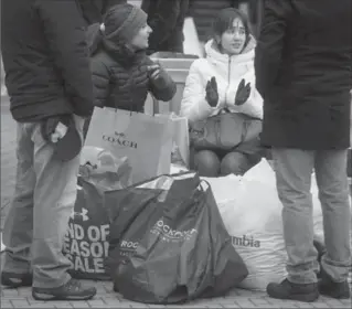  ?? THE CANADIAN PRESS FILE PHOTO ?? Shoppers sit with bags of Boxing Day sale purchases in Richmond, B.C.