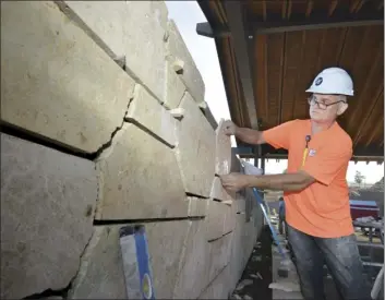  ??  ?? Eugene Ramanov, a mason for Hilltop Contractor­s, fits a piece of coral stone onto a wall at the AC Hotel by Marriott Maui Wailea on Friday morning.