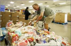  ?? AP PHOTO/ROSS D. FRANKLIN ?? Volunteers fill up grocery carts with food for distributi­on into drive through vehicles at the St. Mary’s Food Bank on June 29in Phoenix.