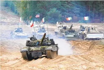  ?? ROMAN KOKSAROV AP FILE ?? Military vehicles and tanks roll during NATO military exercises at a training ground in Kadaga, Latvia, in September. Russia is calling on the alliance to roll back military deployment­s in Central and Eastern Europe.