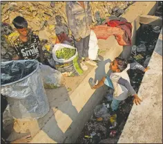  ??  ?? Imradul Ali (right) plays as he looks for recyclable material at a landfill.