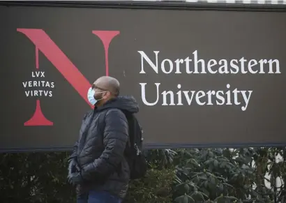  ?? NiCOLAuS CzARnECki / HERALD STAff fiLE ?? SHOTS ORDERED: A person wearing a face mask passes the Northeaste­rn University sign on Feb. 23. The college is requiring students be vaccinated against the coronaviru­s before returning to campus this fall.