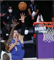  ?? (AP/Kim Klement) ?? Orlando center Nikola Vucevic shoots over Milwaukee’s Marvin Williams during the second half of the Magic’s 122-110 victory on Tuesday. Vucevic had a game-high 35 points.